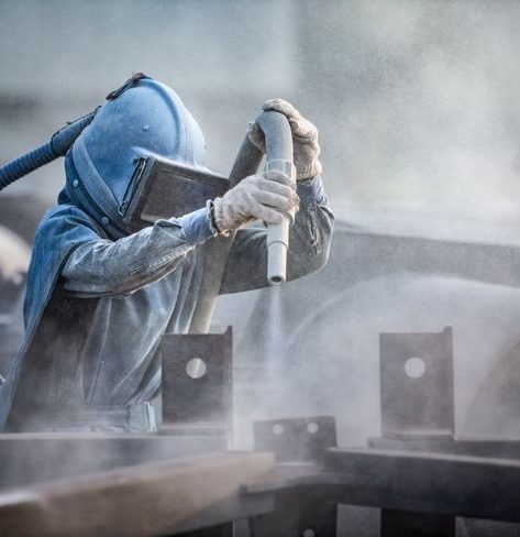 Worker sandblasting a metal surface